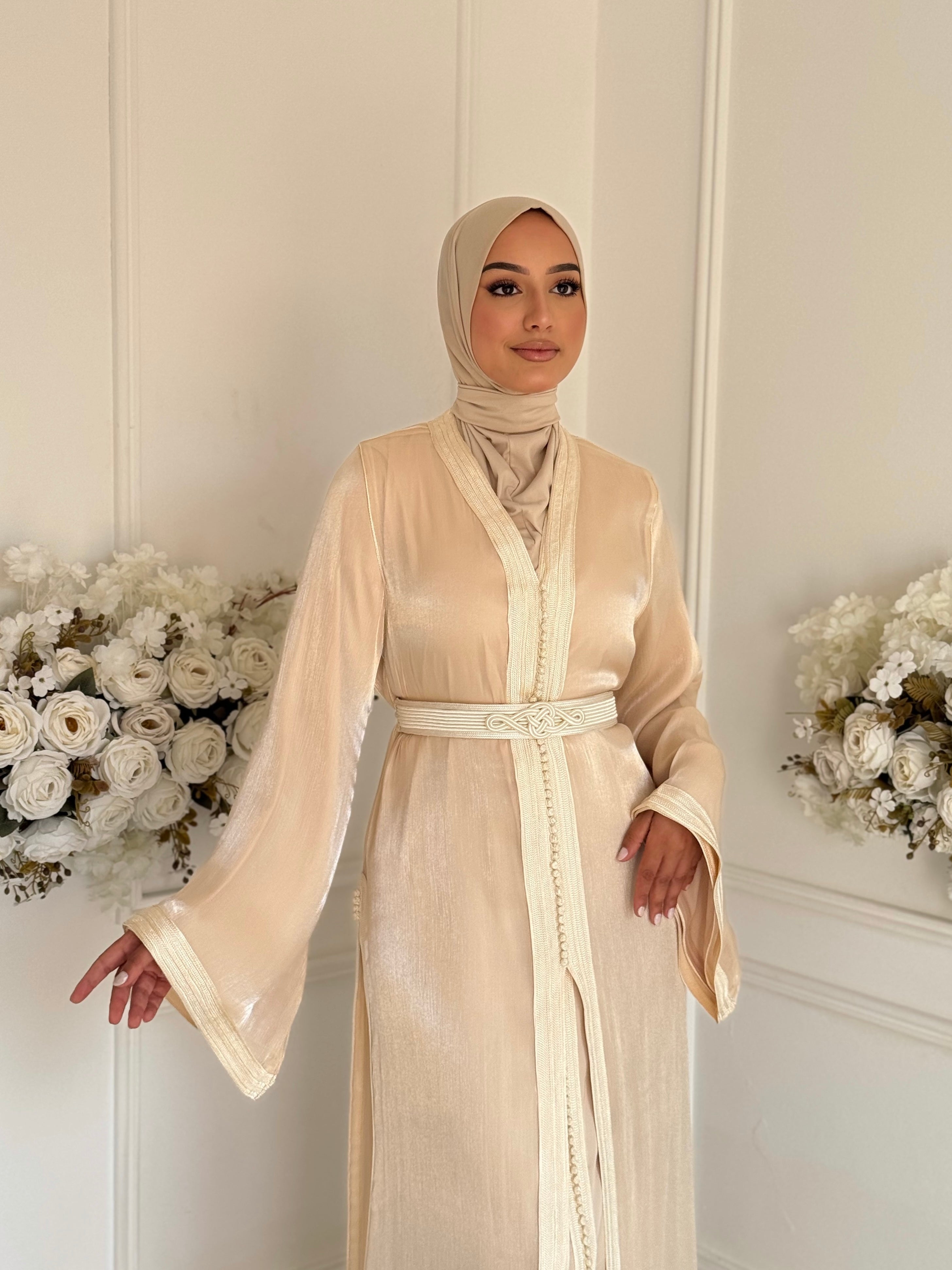 “Woman wearing elegant champagne-colored Moroccan takchita made from organza fabric, perfect for weddings and special occasions.”
